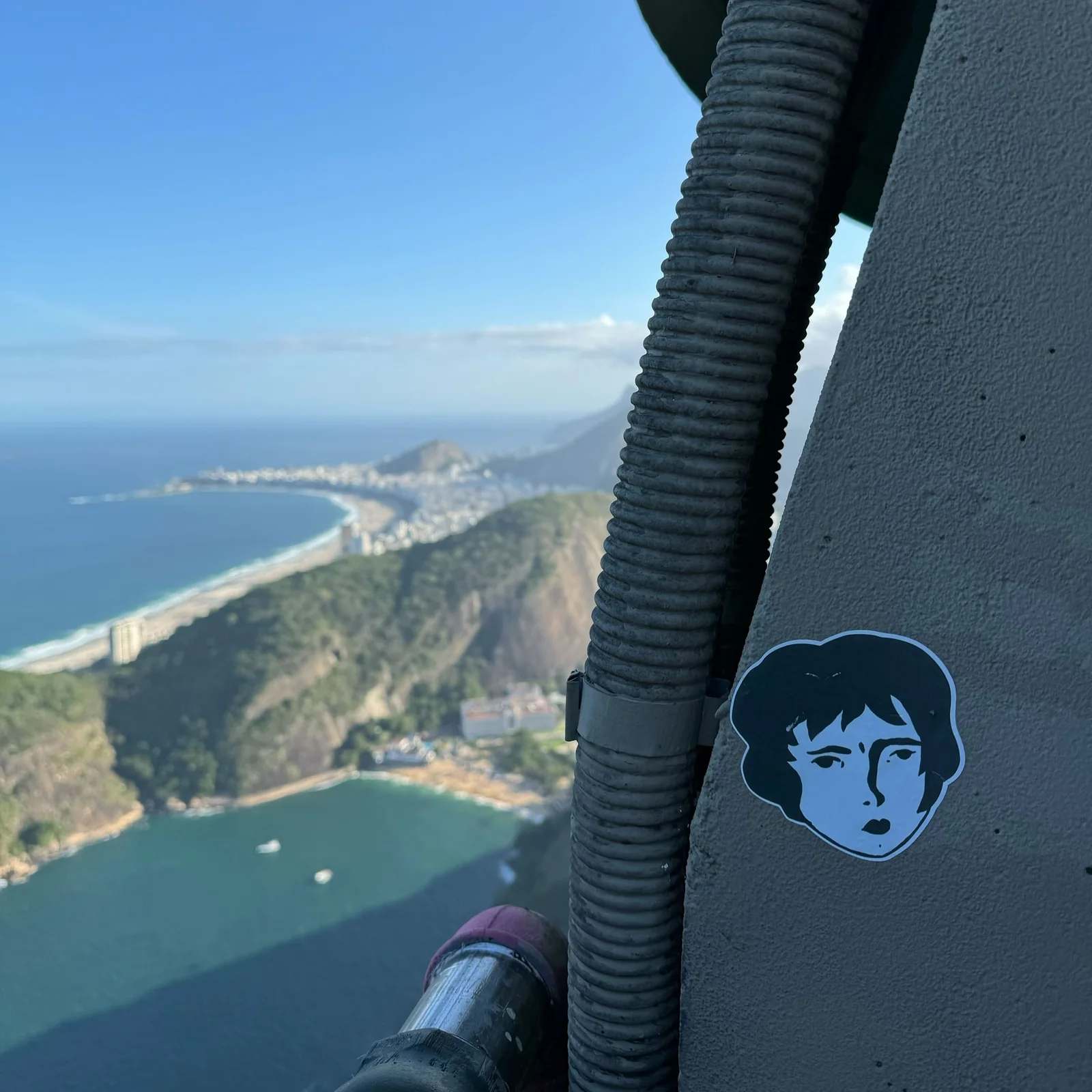A Benzorella sticker on a railing overlooking a coastal city from above