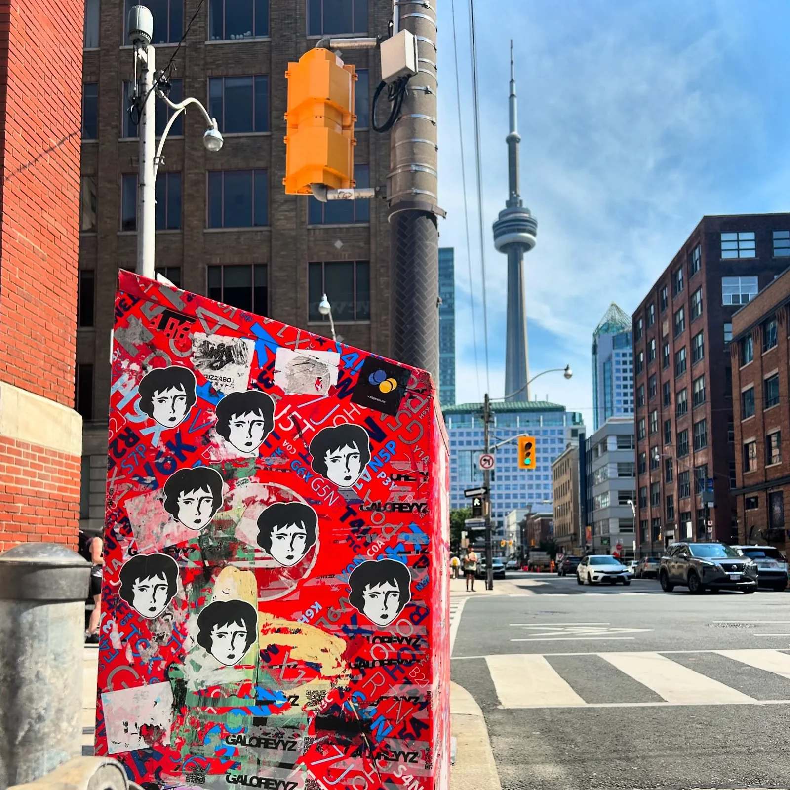 A large red board covered in a pattern of Benzorella faces outdoors