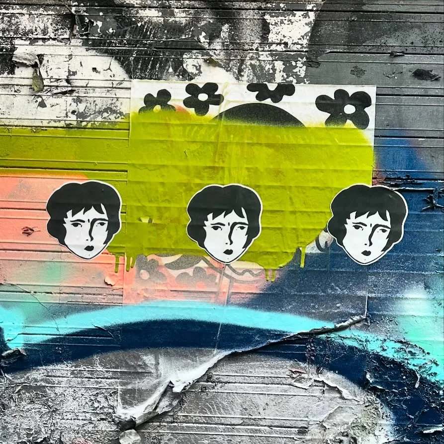 Three Benzorella stickers on a bright blue and yellow painted wall