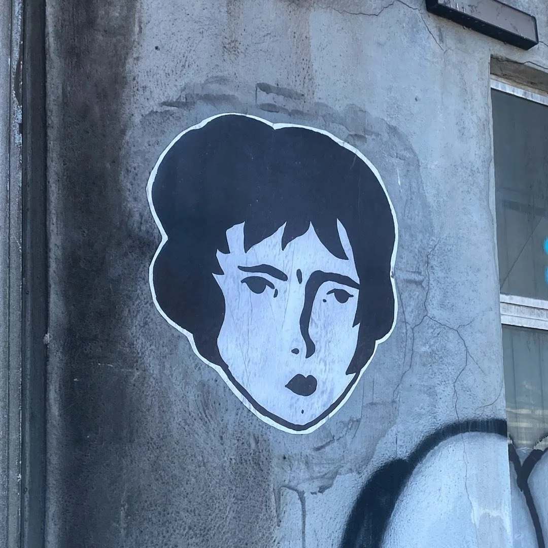 A single Benzorella face paste-up on a light grey weathered wall