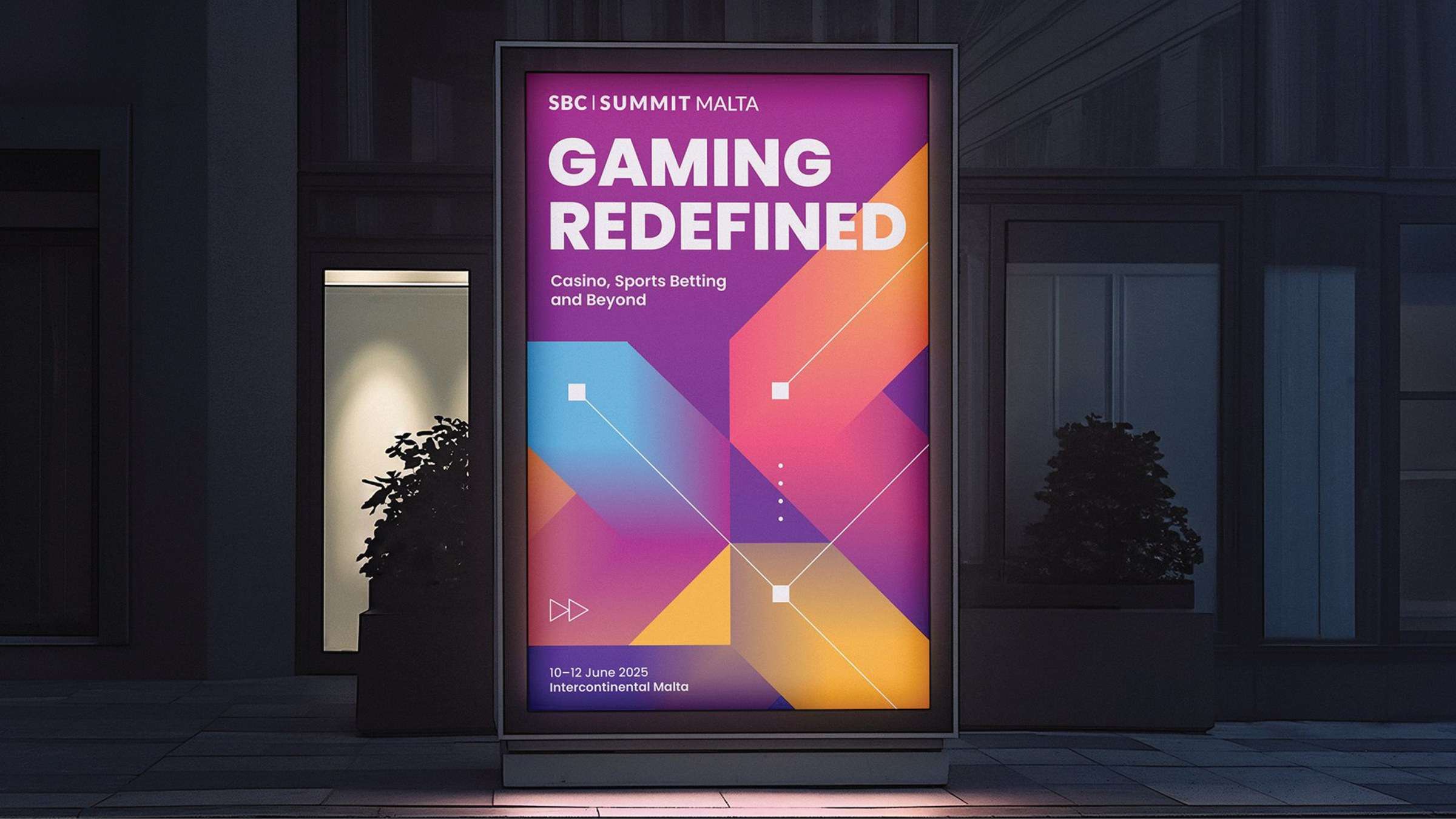 A backlit street poster reading Gaming Redefined in purple, orange and blue geometric shapes